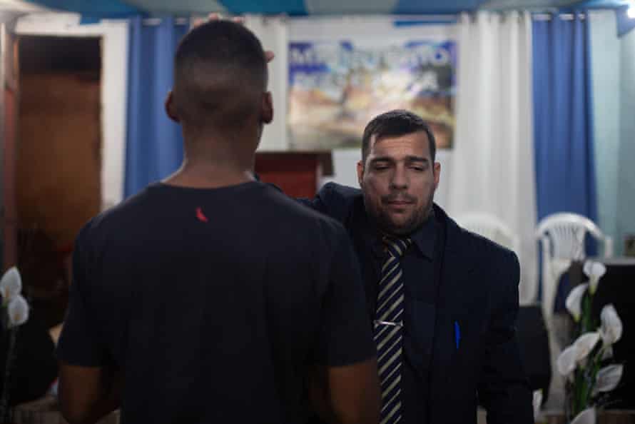 El pastor Elias Santana ora por uno de los jóvenes pandilleros que está tratando de sacar de una vida delictiva