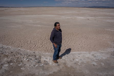 A man stands by a vast salt flat, baked hard by the sun