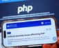 A hand holds a smartphone showing an NCSC webpage warning about a critical PHP security issue