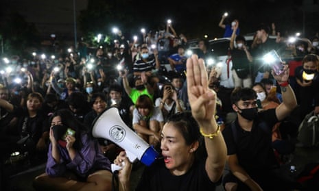 Protesters give the three-finger salute outside the Prachachuen police station in Bangkok