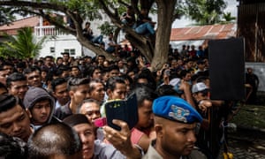 Acehnese people attend the public caning of two young gay men who are said to have violated Sharia law.