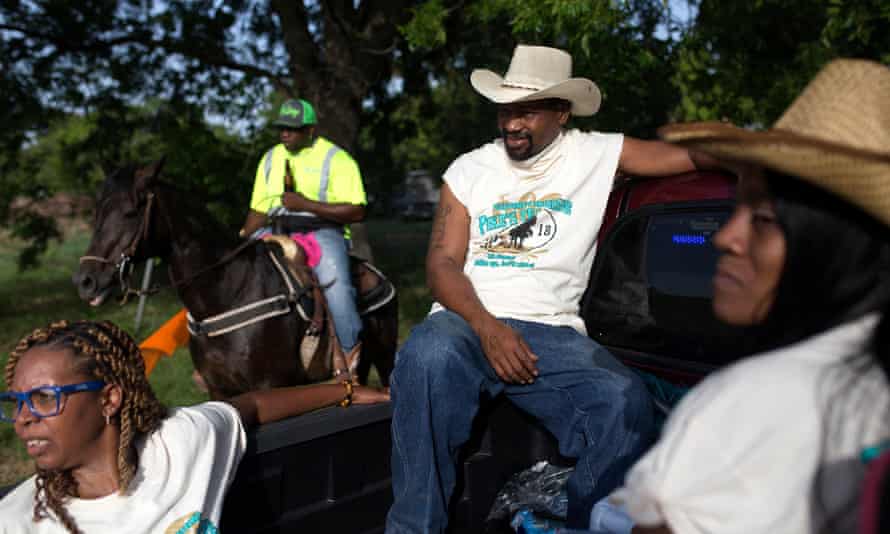 Sonya Jernigan, Derek Reed and Shaniqua Johnson in the back of a pickup truck at the trail ride. Darryl “Dingo” Browning moderates riders on his horse at the trail ride in the background.