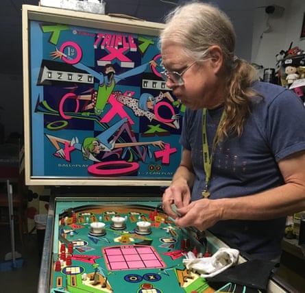Tim Arnold works on the Triple X machine at his pinball hall of fame.
