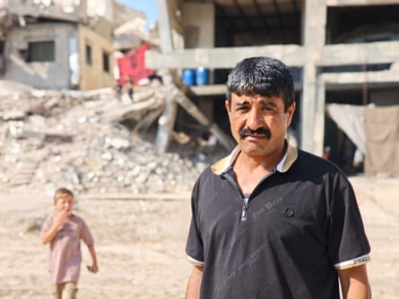 Man dressed in black and child on a street that has been cleared of rubble.