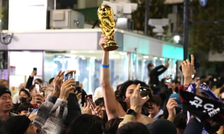 水曜日の夜に東京で開催されたワールドカップで優勝した後、トロフィーを振る日本のサッカーファン。