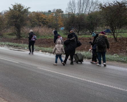 people with bags walk along road