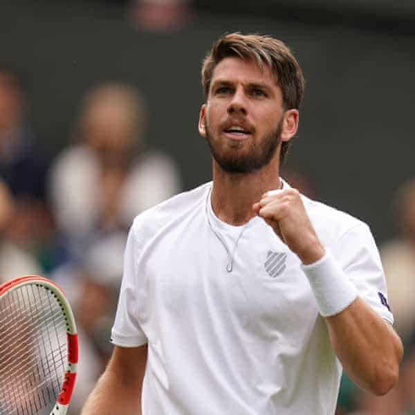 A bearded Cameron Norrie looks up, slightly lifting up his fist