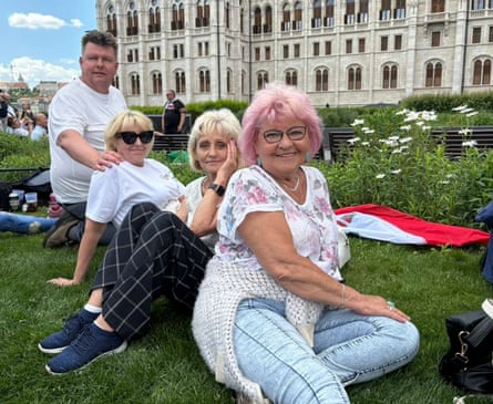 Four people sitting on the grass outside the parliament