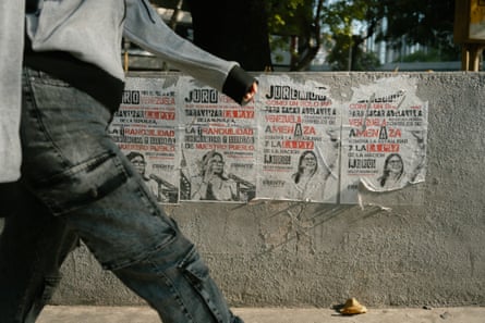 A man walks past tattered posters on a wall bearing the image of Delcy Rodríguez