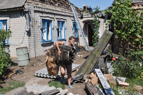 A woman takes out the debris from a house damaged by Russian shelling in Kushuhum.