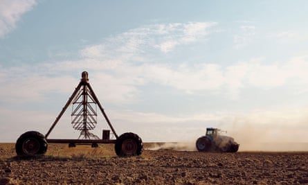 A tractor moving across a dry and dusty piece of land on a farm in South Africa