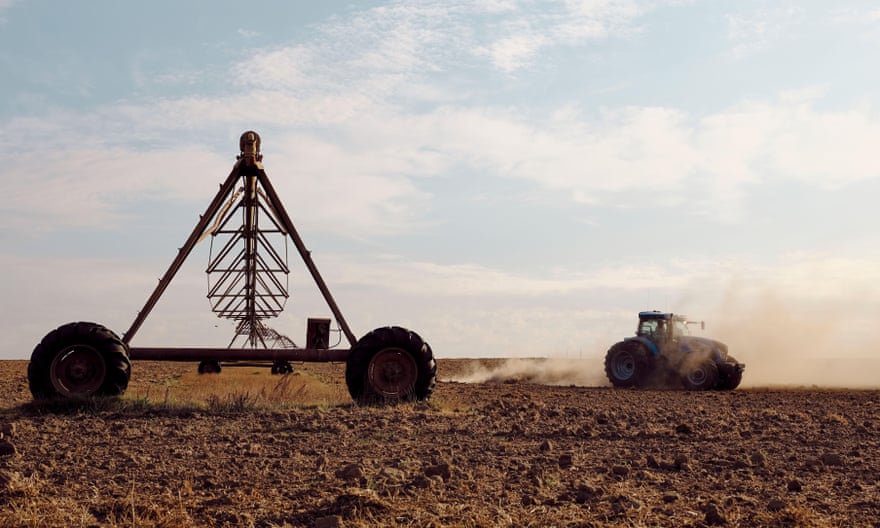 A tractor moves across a dry and dusty piece of farmland in south africa.