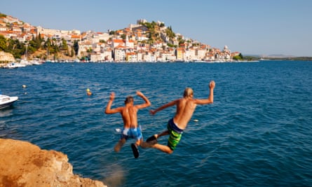 Lads leaping into the sea with town in distance