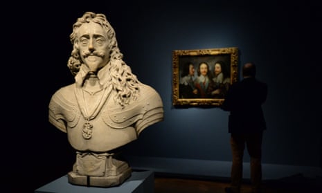 a visitor looks at Charles I in Three Positions by Anthony van Dyck by a statue of the king by Francois Dieussart at the Royal Academy exhibition Charles I: King and Collector.