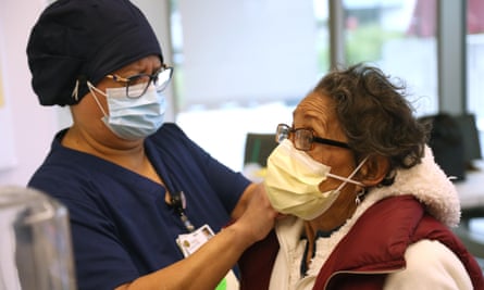 Maria Saravia, left, an Environmental Services Worker at Keck hospital of USC in Los Angeles, tightens the mask of her mother Sara Saravia, 81, before Sara receives the vaccine against Covid-19.