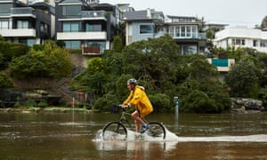 Um ciclista pedala ao longo da trilha inundada em Manly Lagoon em 3 de março, enquanto milhares foram instruídos a evacuar os subúrbios de Sydney devido às fortes chuvas.