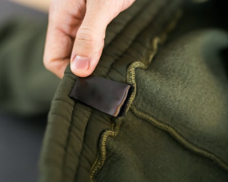A closeup of the inside of green sports trousers showing seams and the label