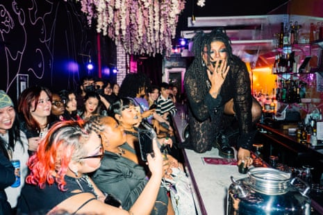 les gens prennent des photos pendant que l'artiste rampe sur le bar