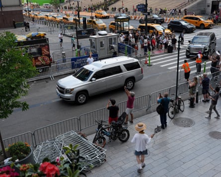 a large silver car drives down a street
