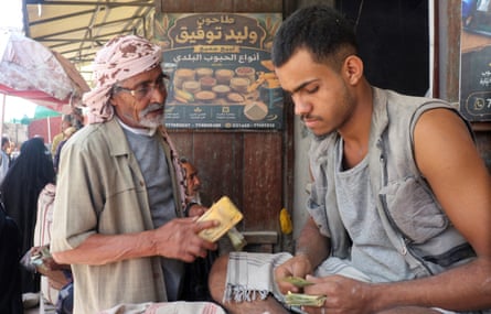 Taiz resident Ali Mahyoub talks to a seller counting banknotes at a grain stall