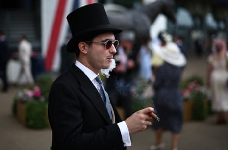 A racegoer enjoys a cigar ahead of racing on the fifth day of Royal Ascot.
