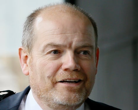 Balding middle-aged white man with stubble in a suit and tie.