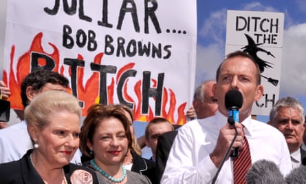Tony Abbott speaking at a rally with a banner behind him saying "JuLiar Bob Browns BITCH'