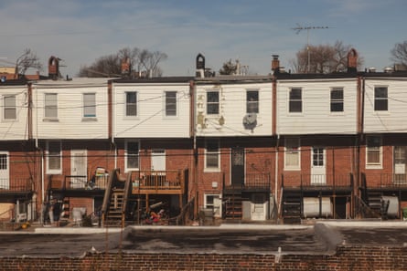 A row of white and brick homes with various power cables and visible needed repairs
