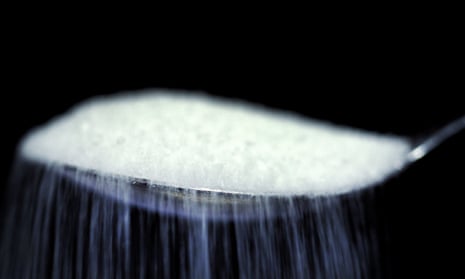 White sugar being sprinkled from a silver tea spoon