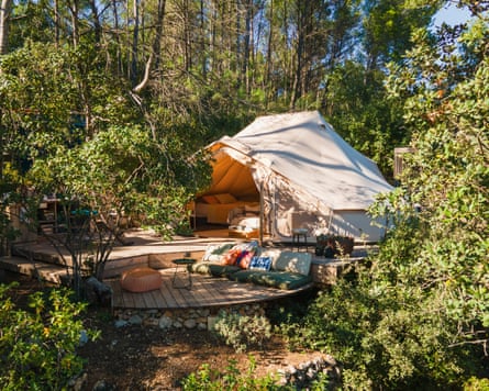 A large bell tent among trees, with seating on decking outside