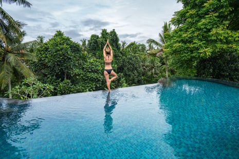 Young woman standing on the edge of an infinity pool, Ubud, Bali.