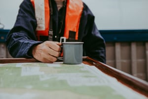 A mug of tea on a table that also holds a map onboard the Salford whelk boat off the north Norfolk coast.
