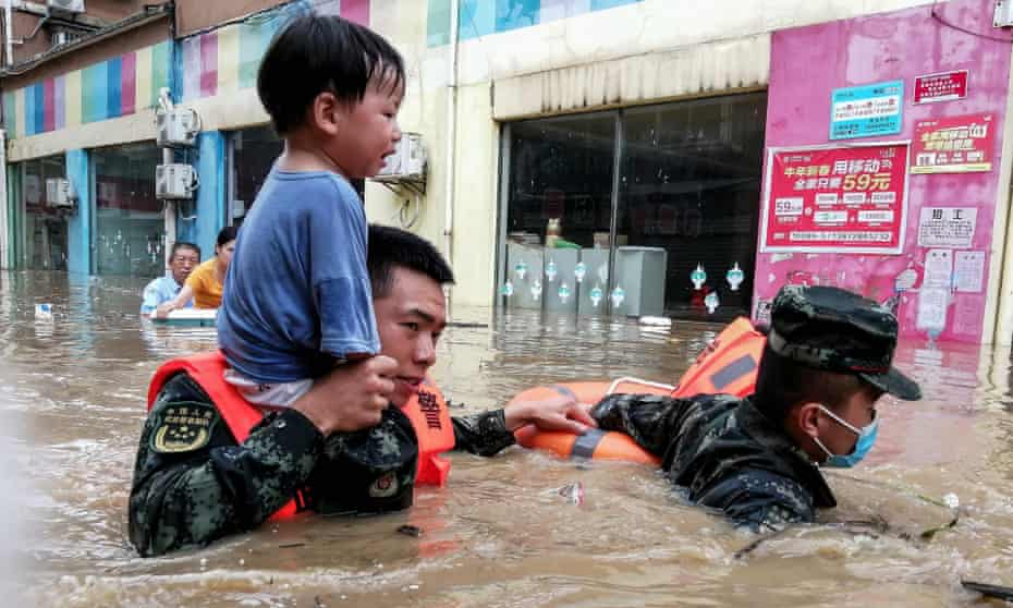 Rescuers evacuate a child from a flooded area in China’s central Hubei province