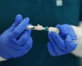Gloved hands prepare a measles, mumps and rubella vaccine, connecting syringe and vial
