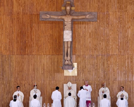 Leo sitting below a large figure of Christ on the cross