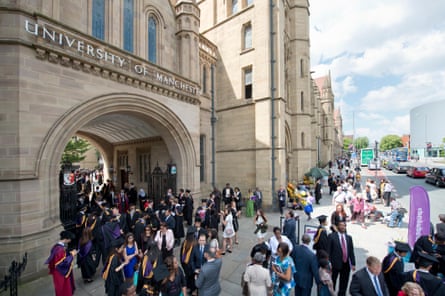 Students in graduation attire enter university building.