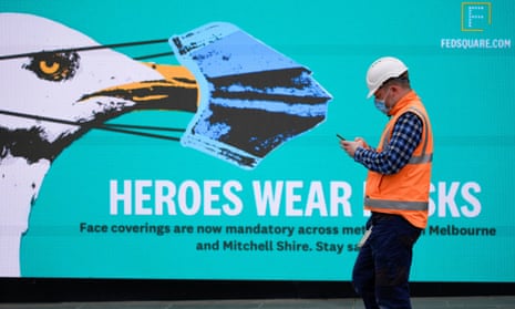 man in hi-viz and mask in front of a heroes wear masks poster