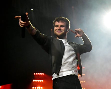 The musician Alex Warren onstage, pointing at the audience