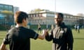 A coach fist-bumps a pupil on a school football pitch