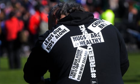 Anti-government protester wearing a black jacket covered in slogans such as Leave our Kids Alone and Hugs are Healthy
