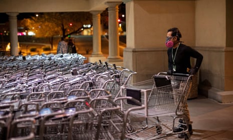 Instacart employee Eric Cohn, 34, picks out a cart outside a Fry’s grocery store while wearing a respirator mask to help protect himself from the coronavirus in Tucson, Arizona.