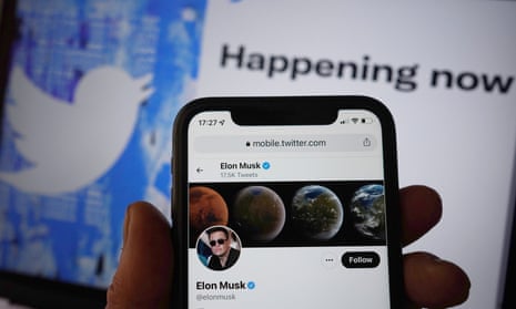 Elon musk's twitter profile on a smartphone held up to a twitter screen