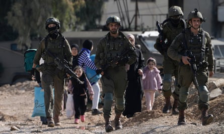 Israeli soldiers walk ahead of women and young girls