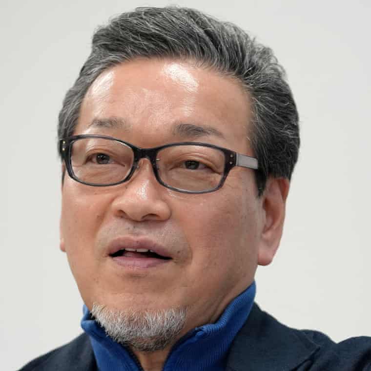 Hidemori Gen, with glasses and a trim goatee and wearing a zip-jumper under a suit jacket, is mid-sentence