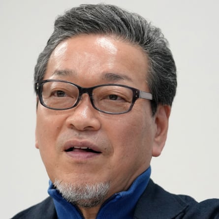 Hidemori Gen, with glasses and a trim goatee and wearing a zip-jumper under a suit jacket, is mid-sentence