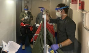 Guardian Angels, a group of medical personnel with the 129th Rescue Wing of the California Air National Guard, working alongside individuals from the Centers for Disease Control and Prevention, don protective equipment after delivering virus testing kits to the Grand Princess cruise ship off the coast of California.