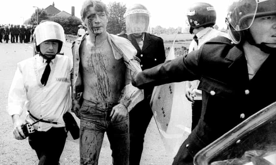 An arrested and injured miner being taken to an ambulance during the industrial action at Orgreave