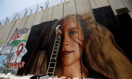 One of the two Italian artists works a mural of Ahed Tamimi on the Israeli separation barrier.