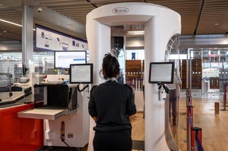 Airport worker stands next to a body scanner