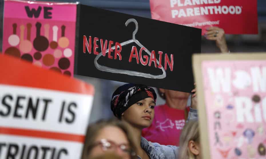 August Mulvihill, of Norwalk, Iowa, center, holds a sign during a rally to protest recent abortion bans, in Iowa on 21 May 2019.